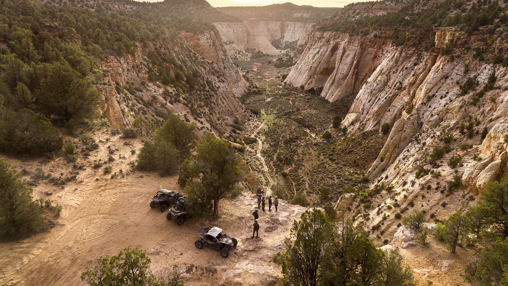 An aerial view of a desert canyon with several drivers and side-by-side Can-Am vehicles