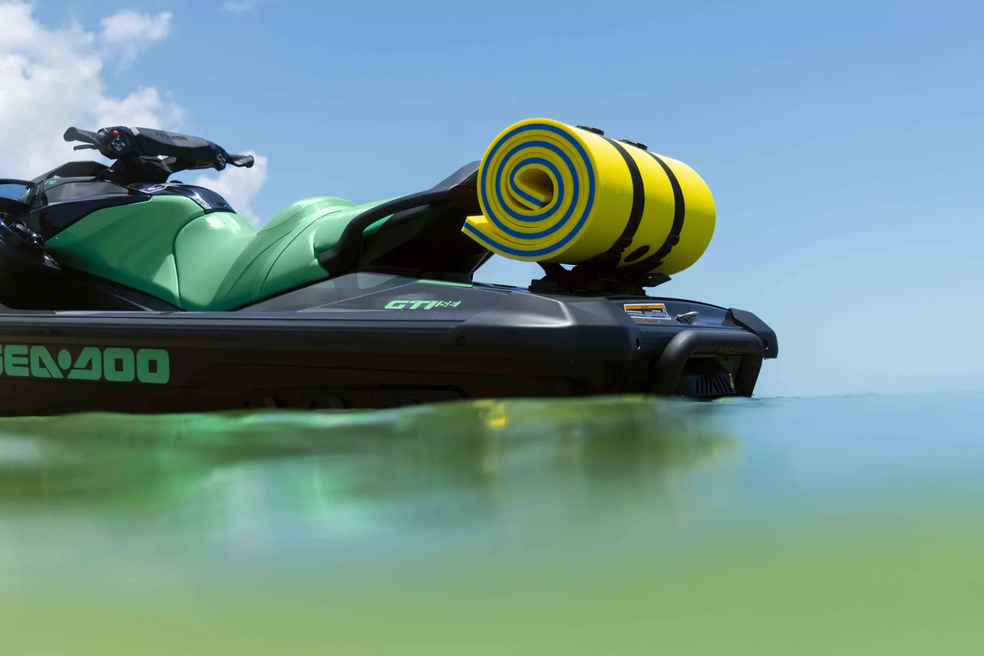 A woman in the water standing next to her Sea-Doo GTI 130 personal watercraft